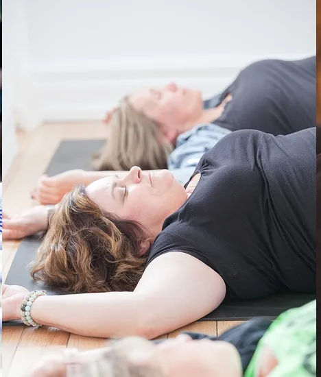 A group resting in stillness on their mats during practice